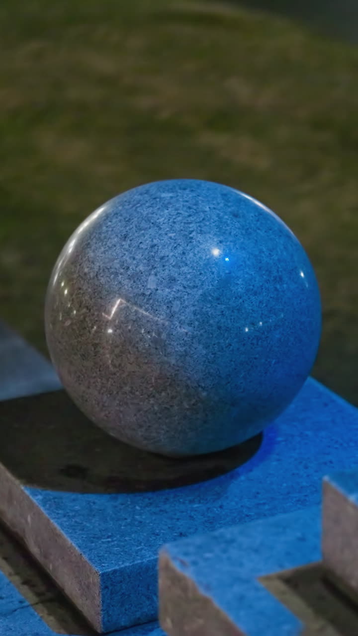 vista lateral de tres esferas de granito iluminadas por la noche, mostrando sus superficies lisas y pulidas y la iluminación suave y azul