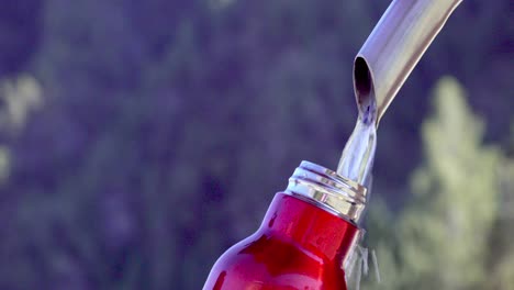 an empty thermos flask is filled with water at a fountain tap