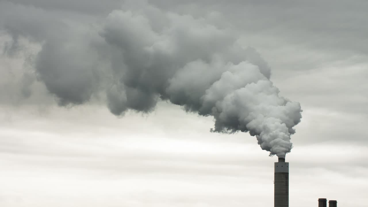 sale humo de una pila de humo de una planta de energía alimentada con carbón con cielo nublado