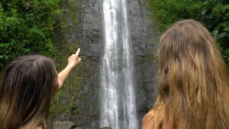 Two-Females-admire-big-waterfall-and-point-to-it-in-slow-motion