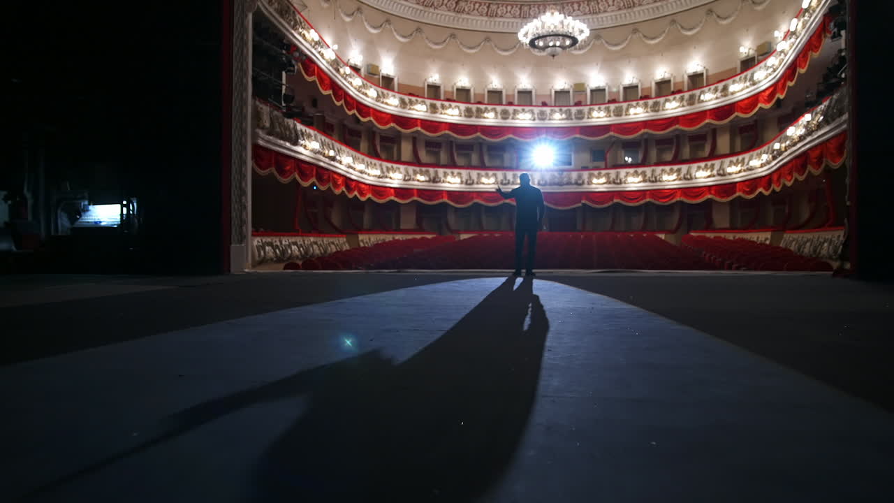 Middle age male entertainer, presenter or actor on stage. Public speaker gives performance. Man in theater.