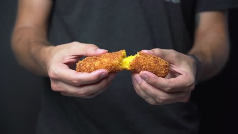 male food blogger pulls a crispy mozzarella croquette apart, medium shot