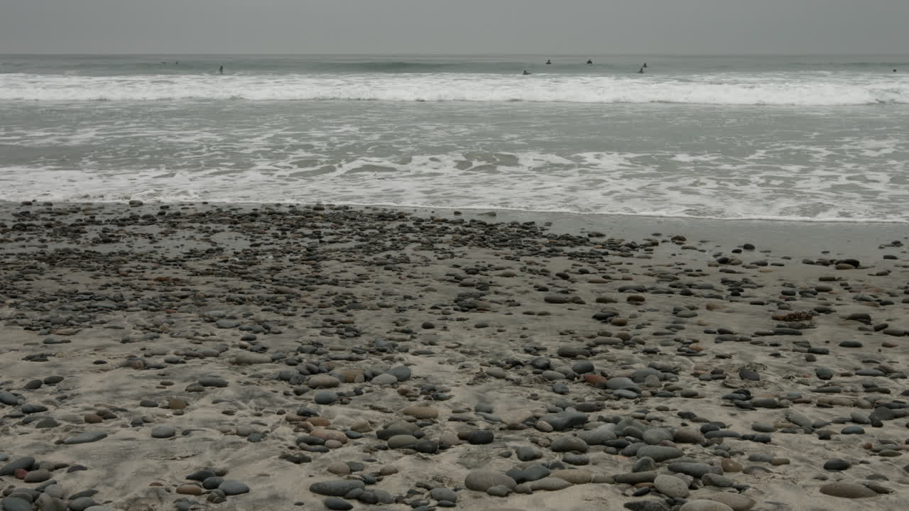 Relaxing waves gently wash over a pebbly beach in Encinitas, California. The rhythmic motion, natural textures, and coastal soundscape create a serene, meditative atmosphere.