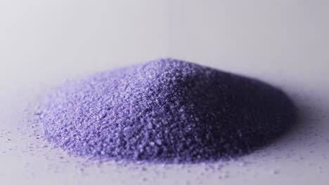 video of close up of heap of purple sand grains and copy space on white background