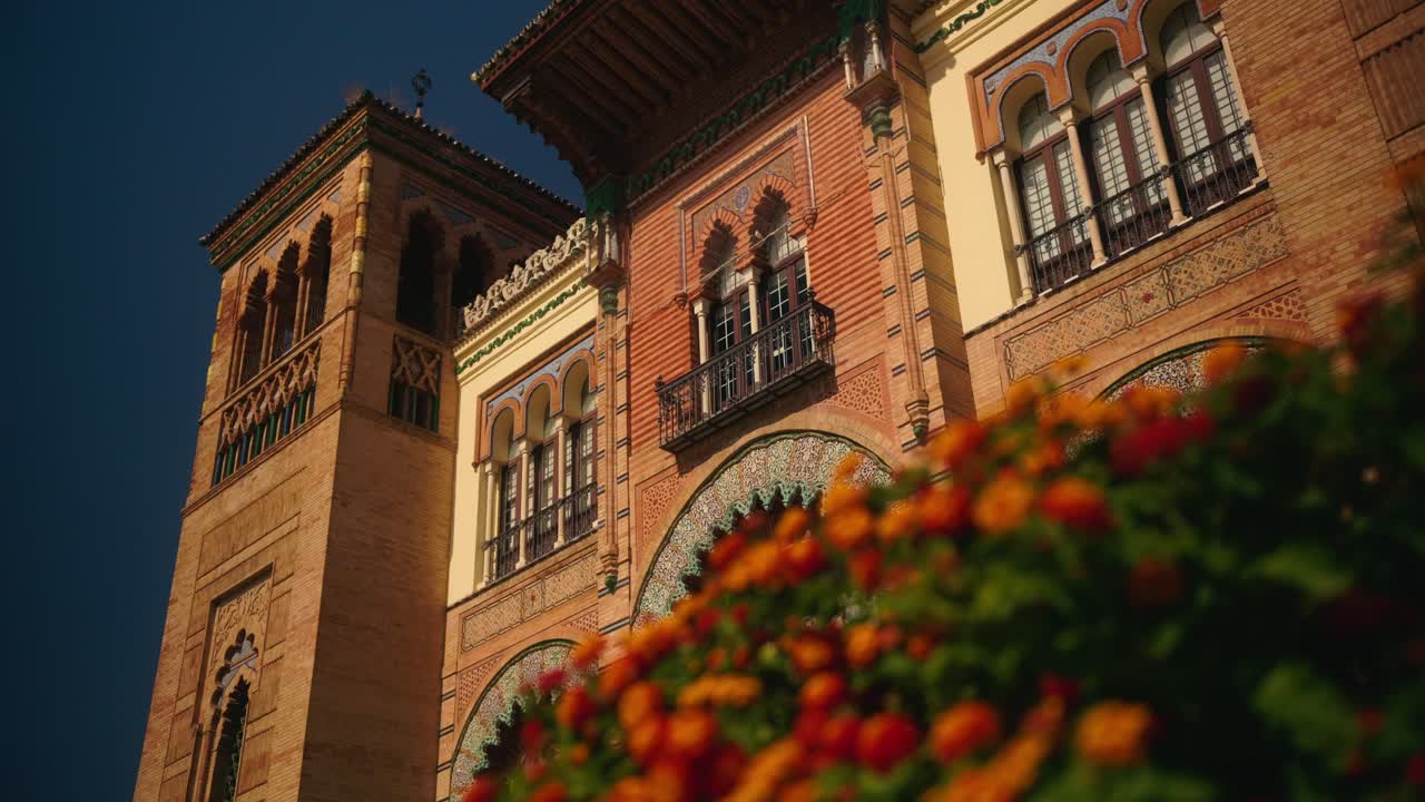 Facciata di edificio storico con archi e fiori colorati.
