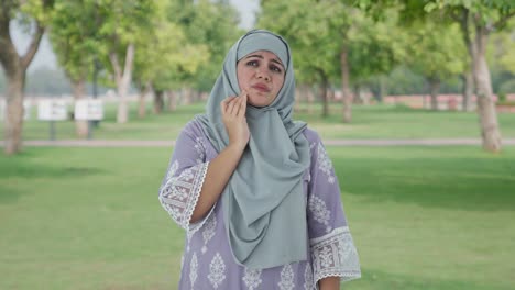 muslim woman suffering from tooth pain in park