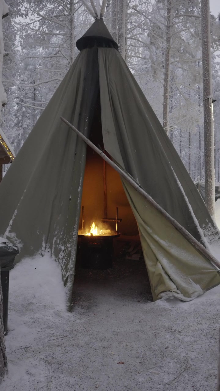 Accogliente falò che brucia all'interno di una tradizionale tenda Lavvu in una foresta innevata
