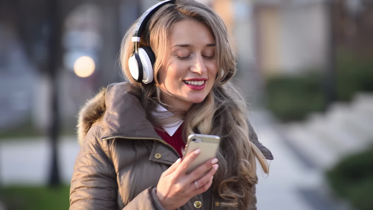 Woman listening to music in her headphones while singing along and dancing in the street