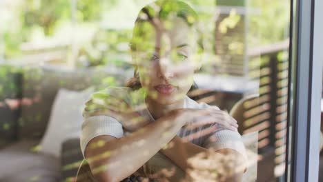 relaxed biracial woman with vitiligo sitting on sofa looking outside, seen through window