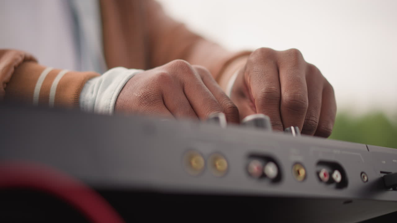 Side black DJ fingers tune mixer, quiet studio atmosphere with precise fader movement, visible ports and cables, focused sound engineering, measured levels and attentive producer technique