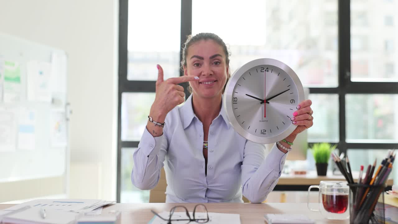 Woman in office holding a clock