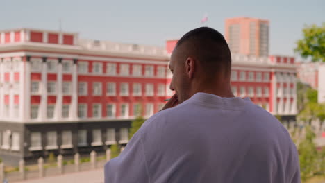 man in terry gown smokes cigarette on hotel room balcony