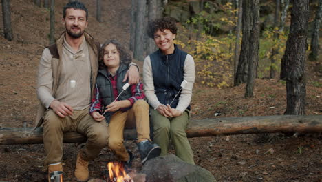 family roasting marshmallows by a campfire in the forest