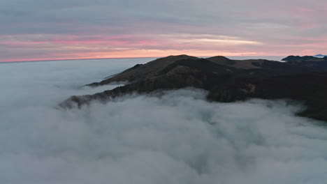 mountain peaks rising above sea of clouds during twilight, serene nature scene, aerial view