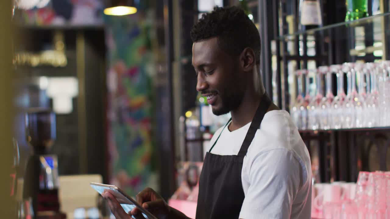 barista afroamericano usando una tableta sonriendo en una cafetería