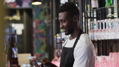 african american barista using tablet smiling in cafe