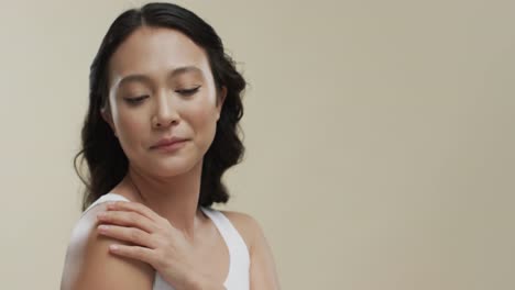 happy asian woman with dark hair on beige background with copy space, slow motion