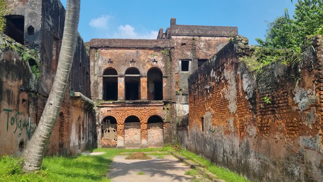Pengungkapan lambat sebuah rumah besar kolonial yang ditinggalkan di Panam Nagar, Bangladesh, bermandikan cahaya matahari musim gugur dan secara bertahap direklamasi oleh tanaman hijau subur alami