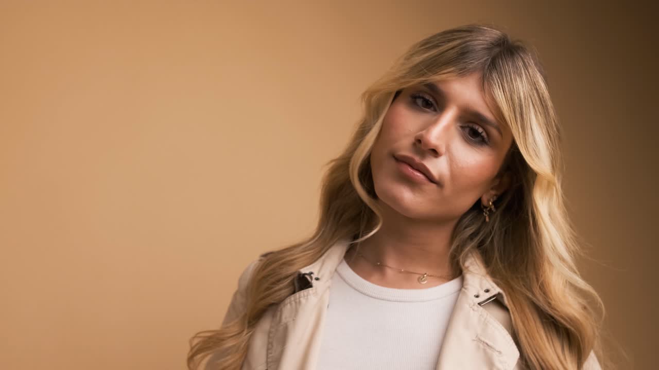 Confident stylish transgender woman posing over beige background