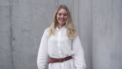 woman in a white shirt posing near a concrete wall