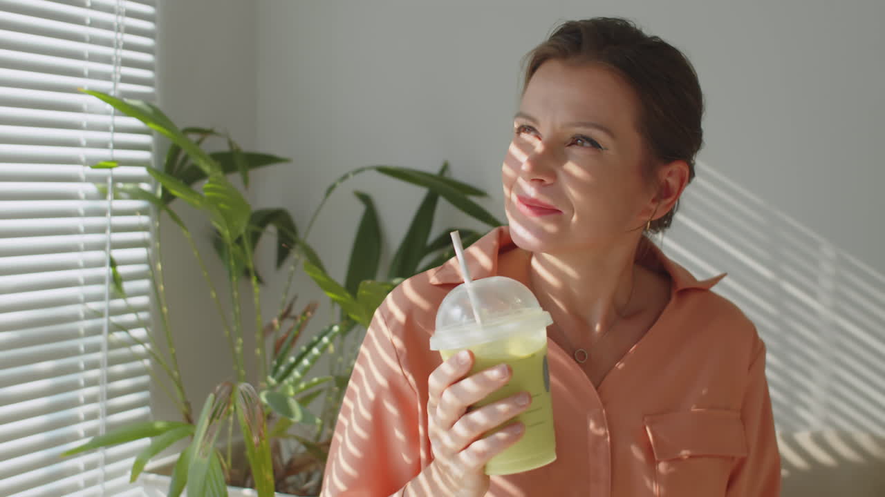 Relaxed Businesswoman Drinking Green Smoothie at Work