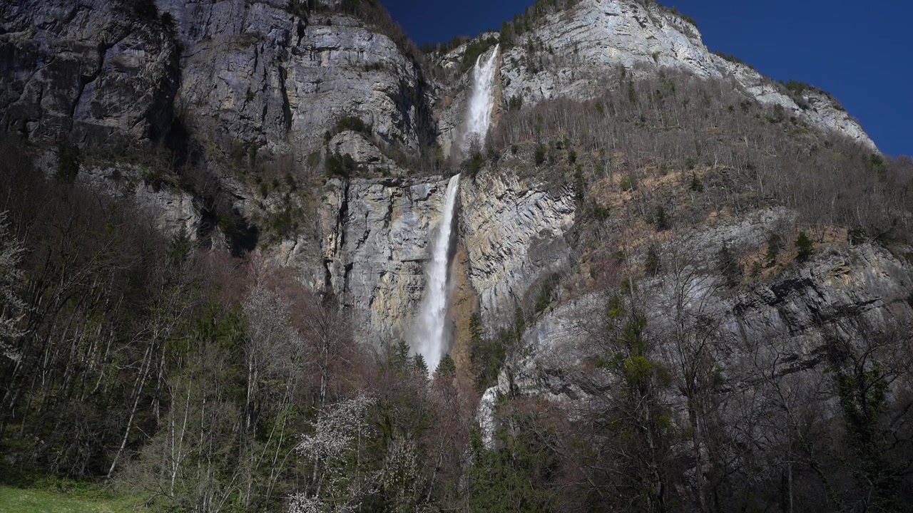 Cachoeira Seerenbachfälle despencando de uma imponente falésia de calcário com floresta na base, em Amden, Suíça.