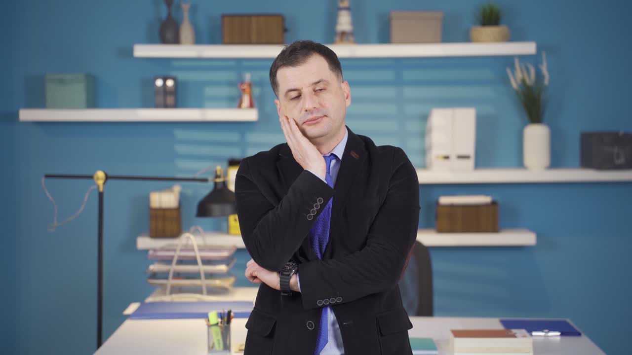 피곤한 사업가가 졸린 눈으로 카메라를 쳐다보고 있습니다.