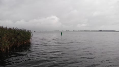 Grüne-Nautische-Boje,-Die-An-Einem-Bewölkten-Tag-Ins-Wasser-Schwimmt-Und-Einen-Kanal-Für-Schiffe-Markiert