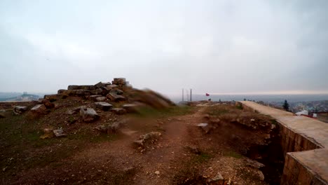 inside ruins and barrier wall of urfa castle on background city snow and rain