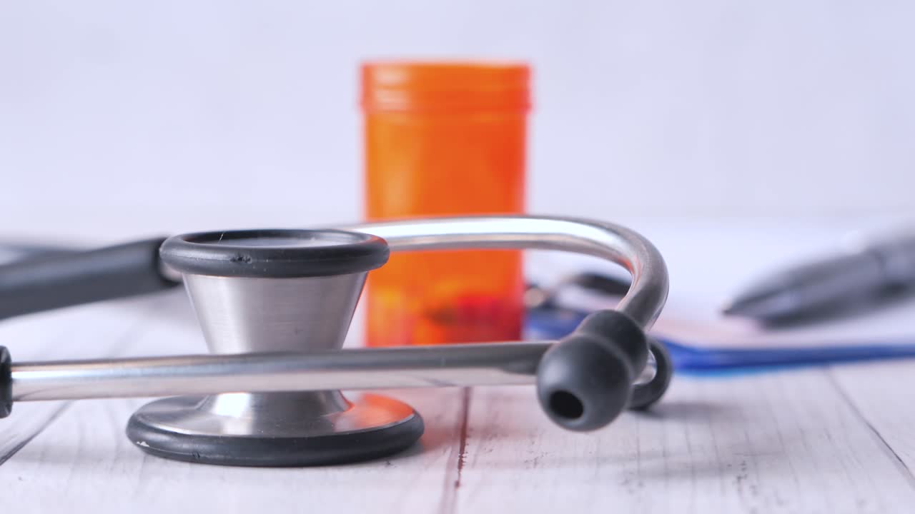 Estetoscopio, pastillas y documentos médicos sobre una mesa