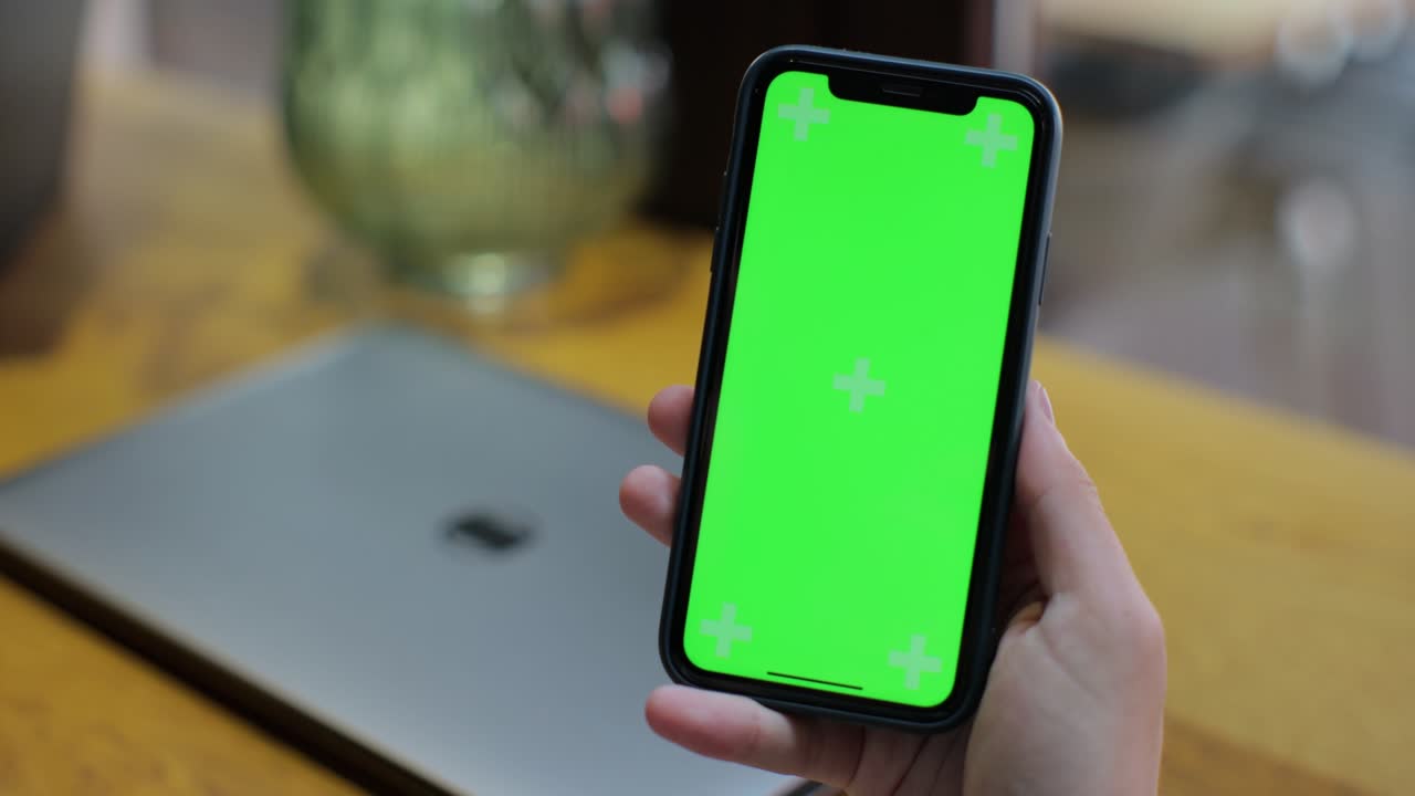 más de la vista del hombro de un hombre usando un teléfono inteligente de pantalla verde en el café. maqueta para el seguimiento. viendo contenido de video blog y navegar por internet.