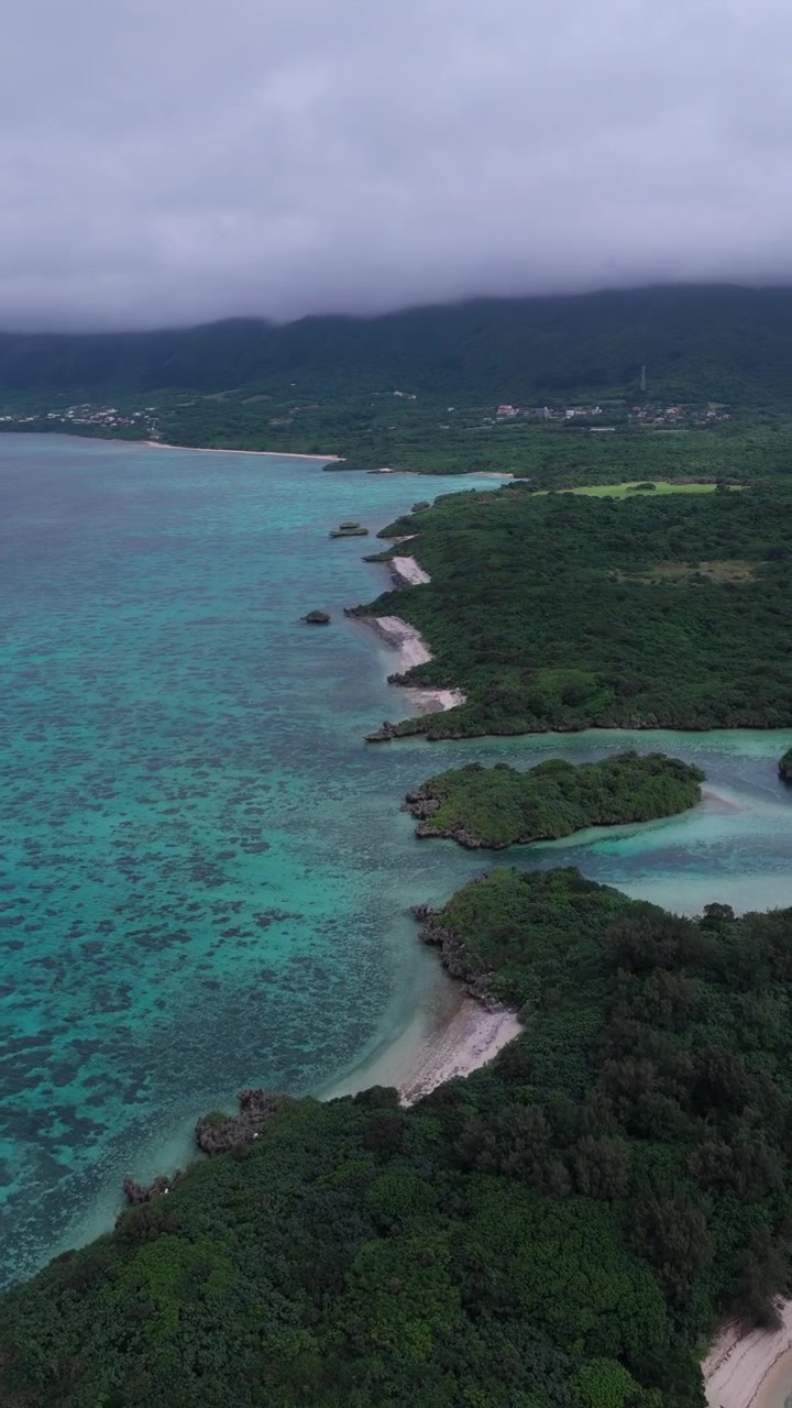 Riprese aeree verticali che avanzano e panoramicano delicatamente a destra sopra il Canale di Kabira Bay e la costa della barriera corallina sull'isola di Ishigaki, Isole Yaeyama, Okinawa, Giappone.