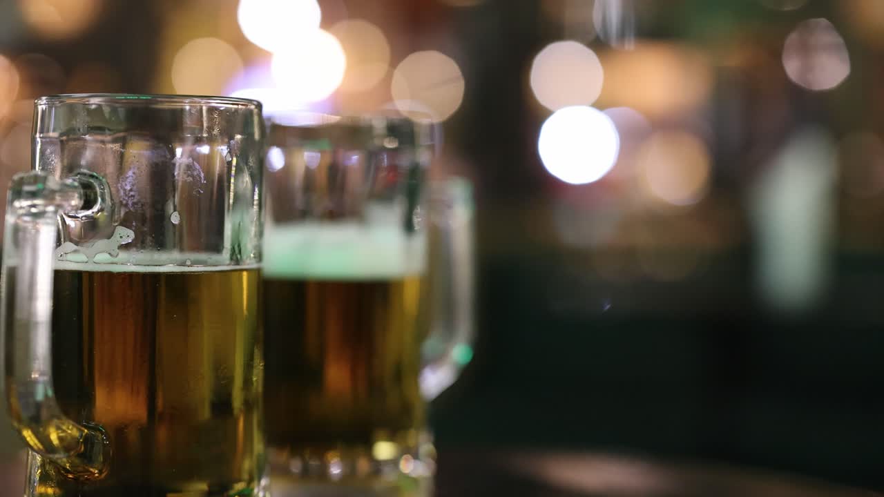 A series of beer glasses on a table in a dimly lit, bustling street setting with blurred background lights