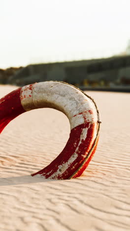 red and white life preserver on a sandy beach