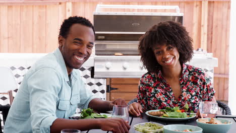 Una-Joven-Pareja-Negra-Sentada-En-Una-Mesa-Afuera-Mirando-A-La-Cámara