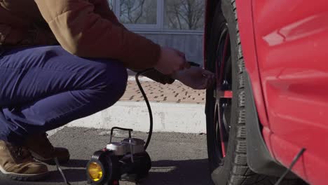 Closeup-portrait-of-a-man-checking-pressure-and-pumping-a-car-tire.