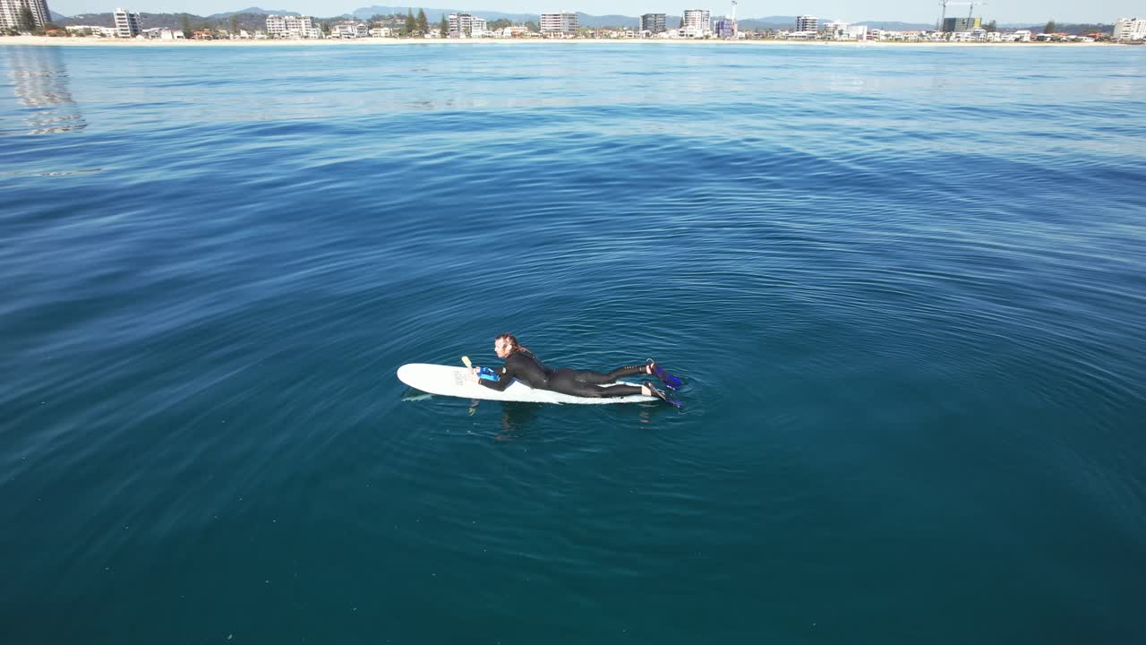 Surfer Lying On Surfboard And Floating On Calm Ocean - Drone Shot