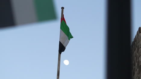 scenic view of uae flag and moon in the sky in deira, dubai on a sunset - medium shot