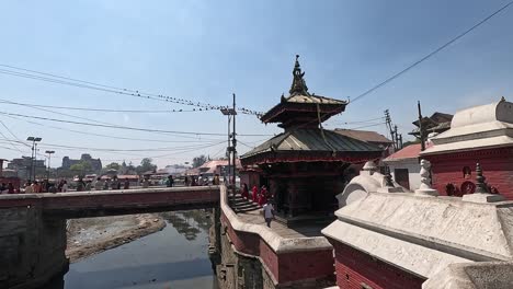 pashupatinath temple cremation complex on the banks of sacred bagmati river in kathmandu, nepal. overlooking white mausoleums, roofs of pandra shivalaya