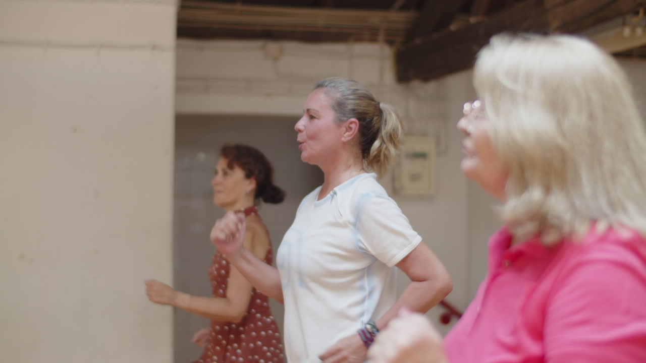 Vista lateral de mulheres seniores correndo no mesmo lugar em estúdio de dança