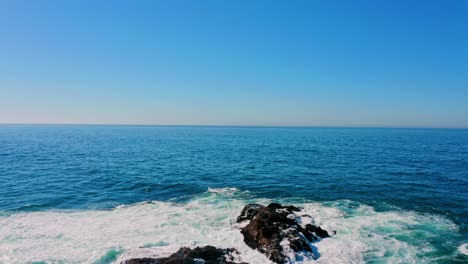 waves hitting a rock in the middle of the pacific ocean.