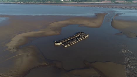 two wrecked freighters side by side in estuary mud