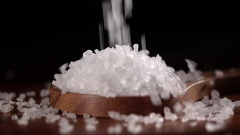 sea salt crystals closeup in wooden spoon on a kitchen table.