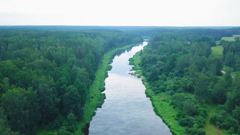 aerial view of a venta river on a sunny summer day, lush green trees and meadows, beautiful rural landscape, high altitude wide angle drone shot moving forward