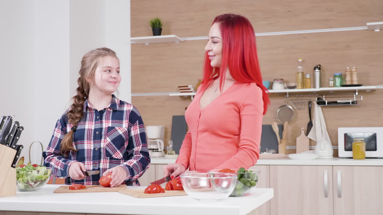 Mother and daughter cooking salad in the kitchen
