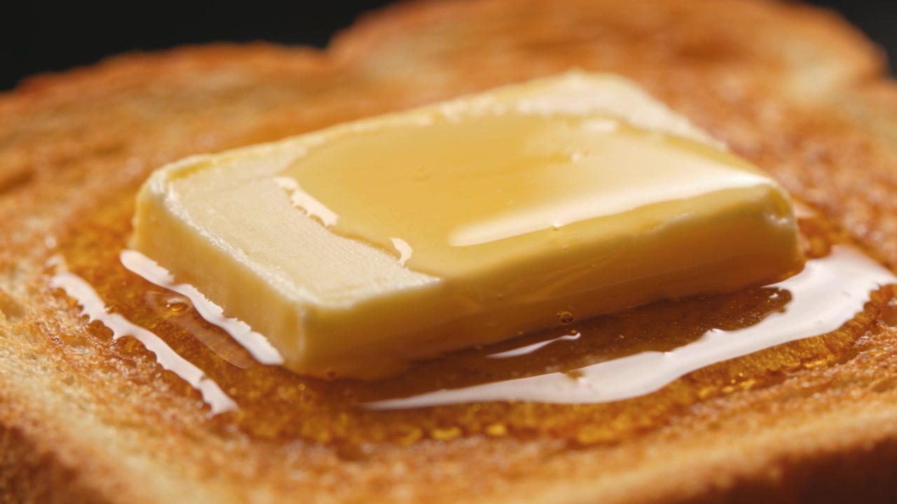 Mantequilla derritiéndose sobre pan tostado caliente en el estudio, con sirope esparciéndose.