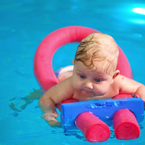 cute infant baby swimming on the pool foams tick. close up. swimming lessons for newborn.