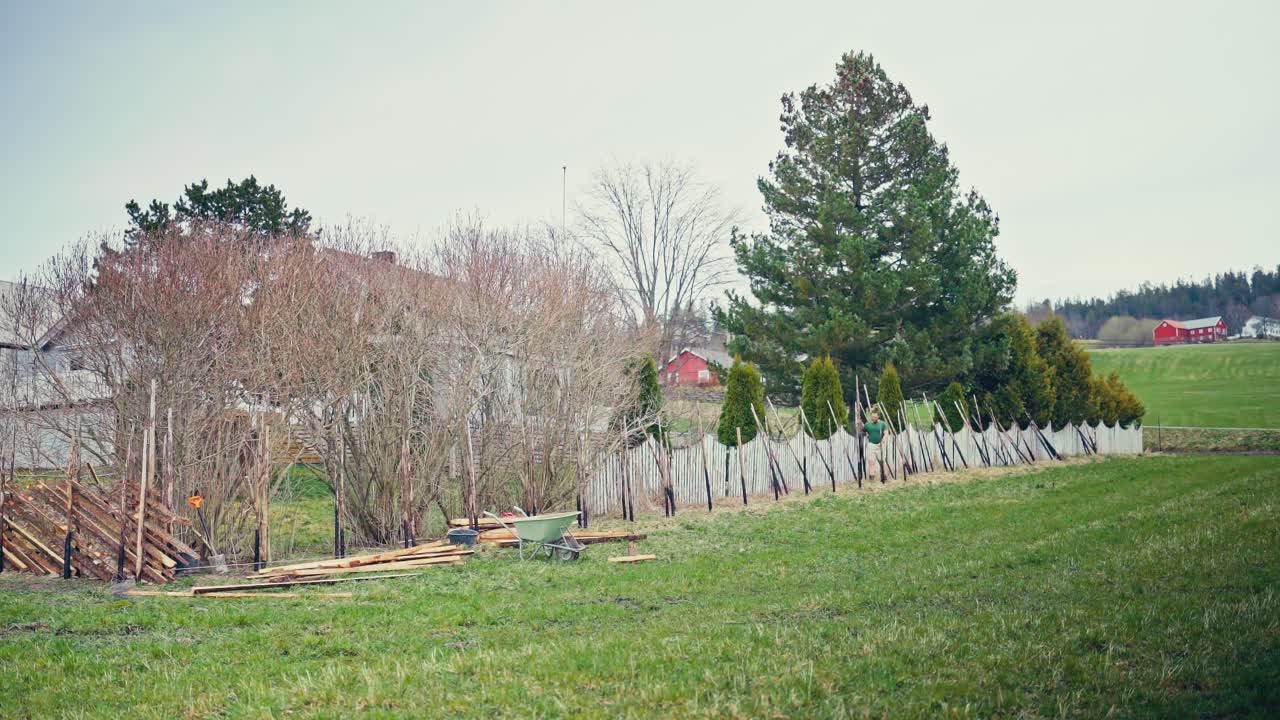 A Person Constructing A Wooden Barrier In A Countryside Village. Timelapse
