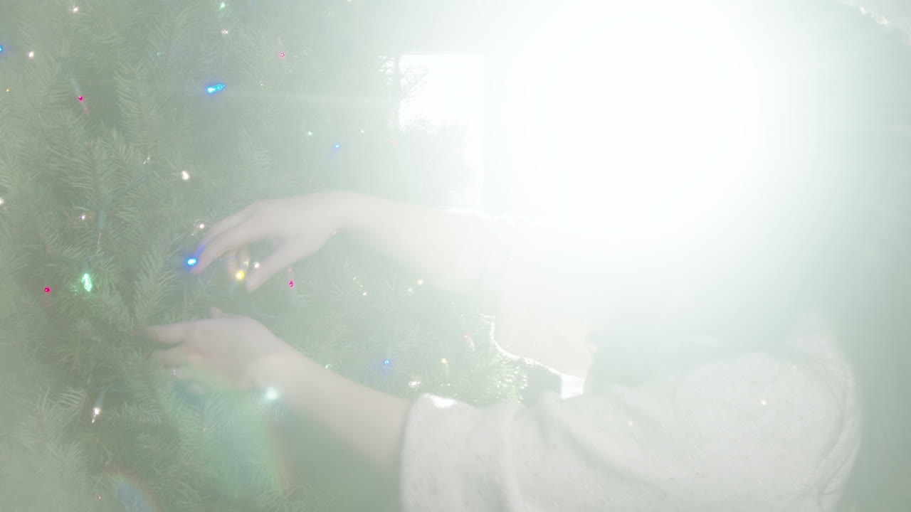 Woman Decorating a Christmas Tree with Colorful Lights