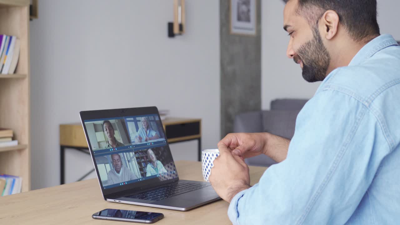 Intialainen mies videopuhelussa monimuotoisen ihmisryhmän kanssa tietokoneella, sivukuva.